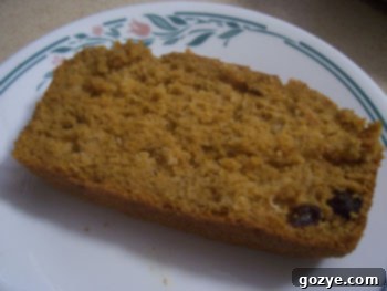 A beautifully golden-brown loaf of Pumpkin Raisin Bread cooling on a wire rack, showcasing its moist texture and visible plump raisins.