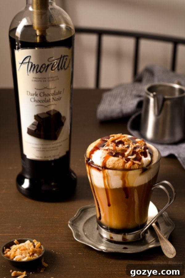 Two mugs of hot Toasted Coconut Mocha with whipped cream and toasted coconut, on a wooden surface.
