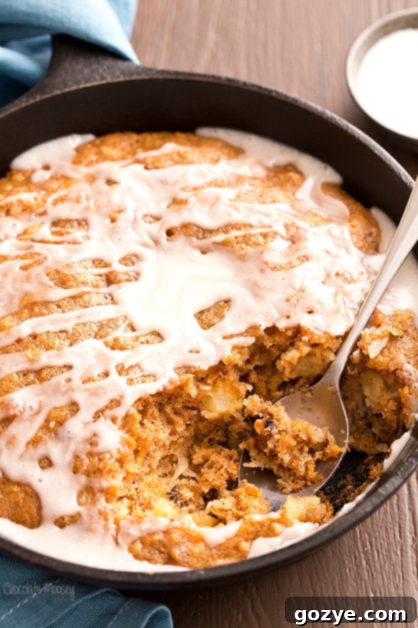Close-up of a moist slice of Carrot Cake Skillet Cake with a perfectly set vanilla glaze.