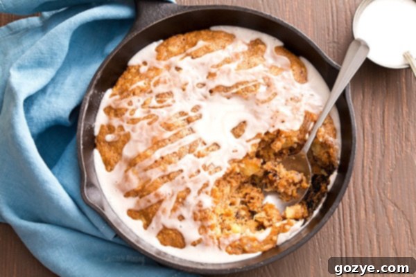 Drizzling homemade vanilla glaze over the freshly baked Carrot Cake Skillet Cake in a cast iron pan.