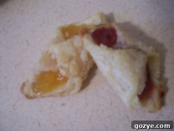 Golden Kolacky pastries on a plate, lightly browned and filled with fruit preserves.
