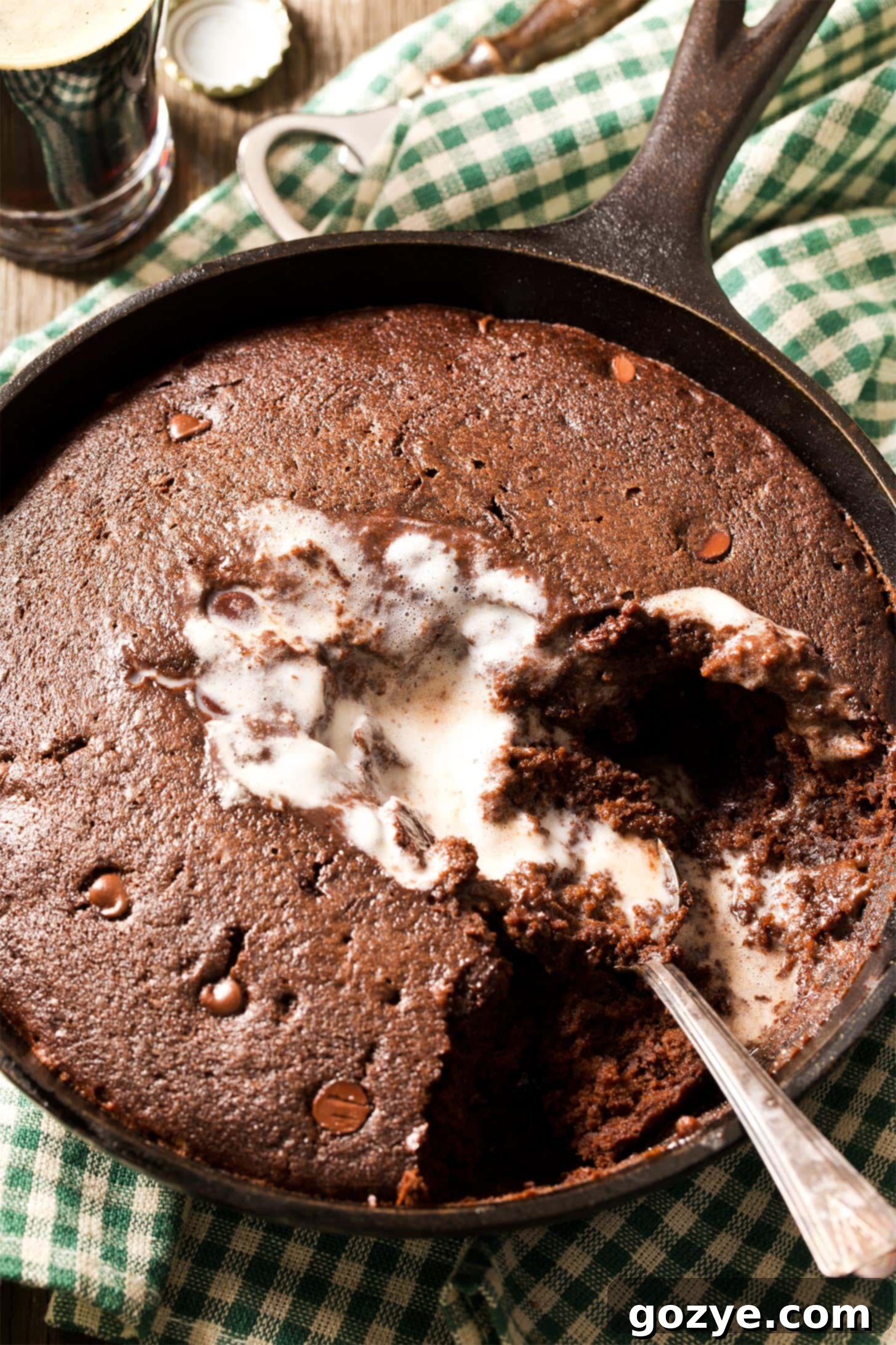 Spoon digging into warm chocolate cake in a skillet, showcasing its moist texture