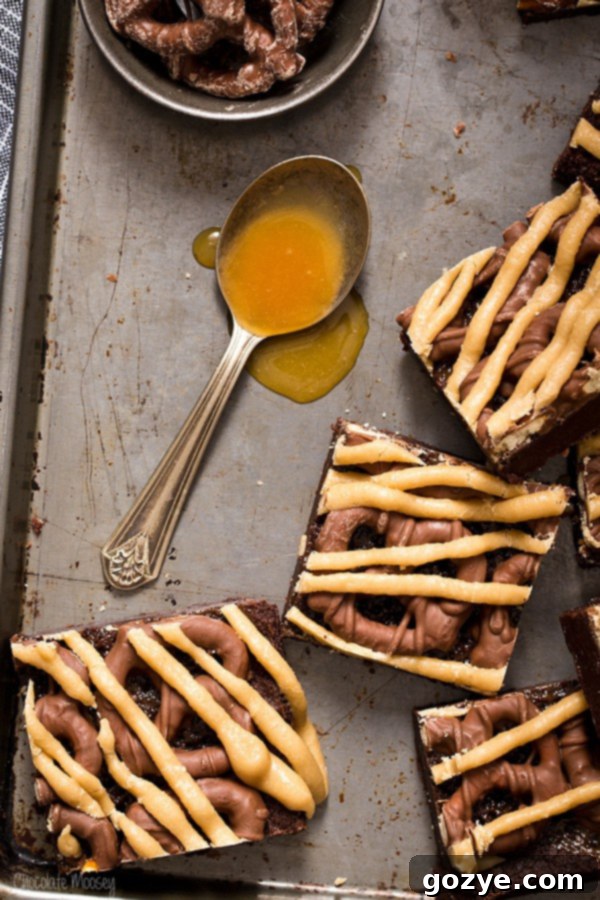 Freshly baked Chocolate Covered Pretzel Caramel Brownies topped with chocolate pretzels and drizzled caramel glaze