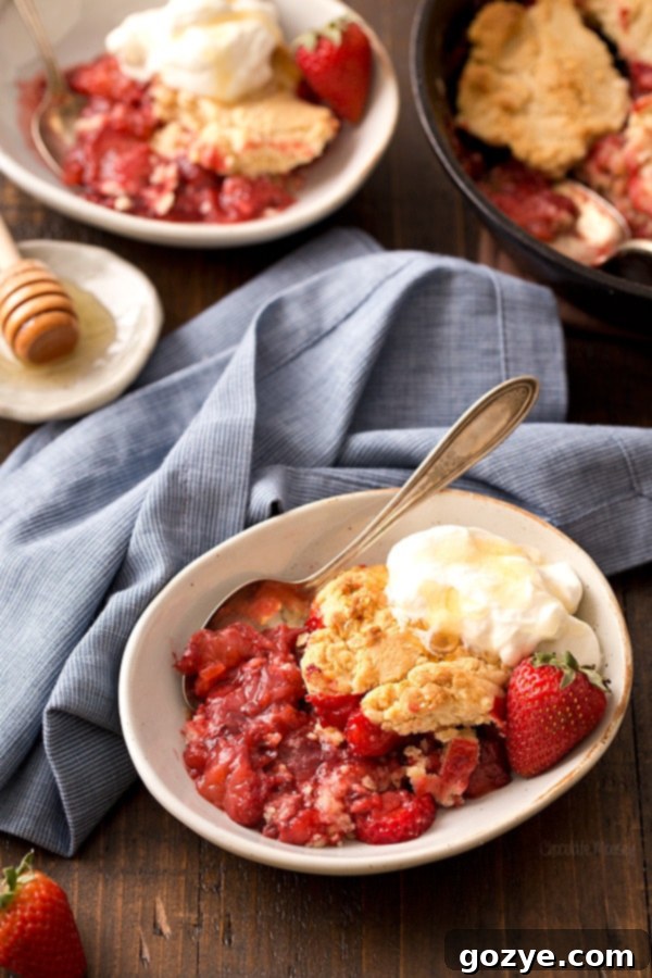 Bowl of strawberry cobbler with honey biscuit and honey whipped cream on top