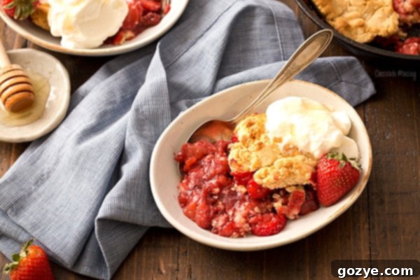 Easy homemade strawberry cobbler in a bowl with generous honey whipped cream