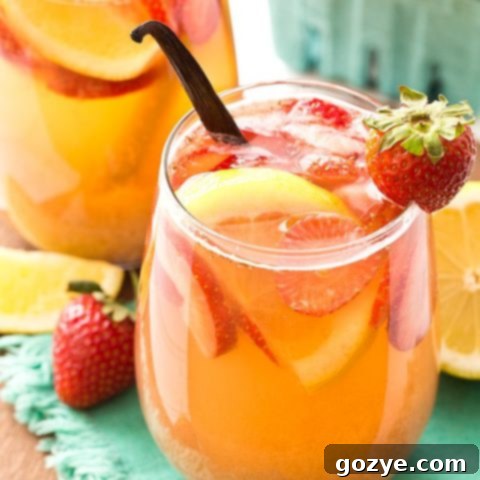 A glass of Strawberry Vanilla Sangria garnished with fresh strawberries and a lemon slice.