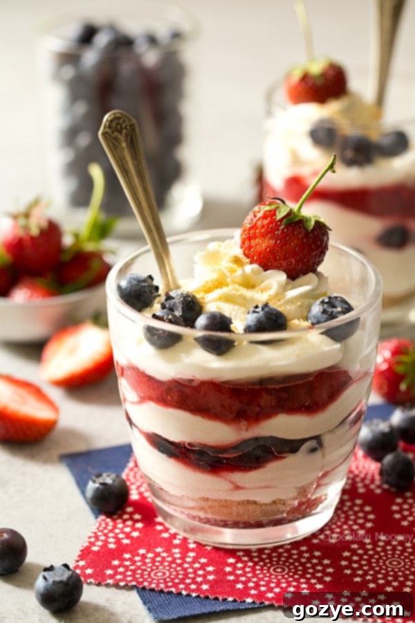 Close-up of a Red White and Blue Cheesecake In A Cup with a spoon, showing the creamy layers and fruit.