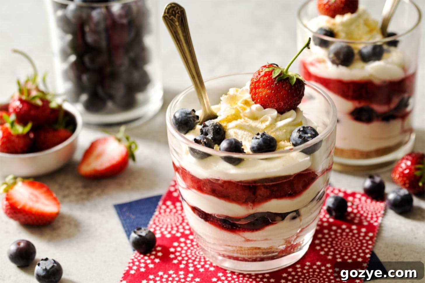 Cheesecake Parfait Dessert in clear glasses topped with fresh strawberries and blueberries, ready for serving.