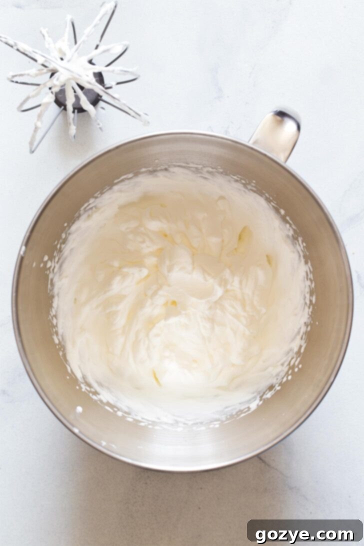 Making homemade whipped cream by beating cold heavy cream, powdered sugar, and vanilla in a mixing bowl until stiff peaks form.