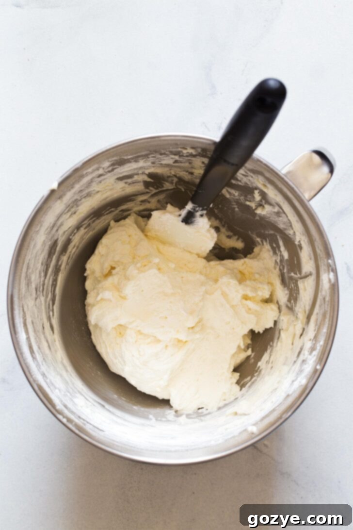 Gently folding the prepared whipped cream into the cream cheese mixture until fully incorporated, creating a light and airy no bake cheesecake filling.