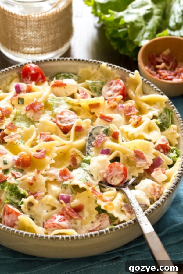 Close-up of creamy Bacon Ranch Pasta Salad in a large serving bowl with a serving spoon, showcasing the ingredients
