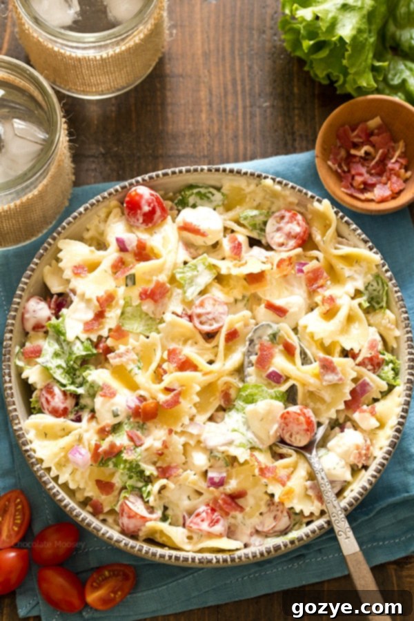 Overhead shot of a large, rustic bowl brimming with BLT Pasta Salad, featuring an array of pasta, bacon, tomatoes, and mozzarella