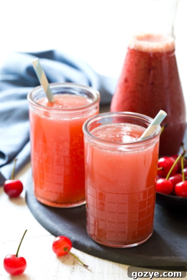 Glass of homemade cherry cream soda garnished with fresh cherries.