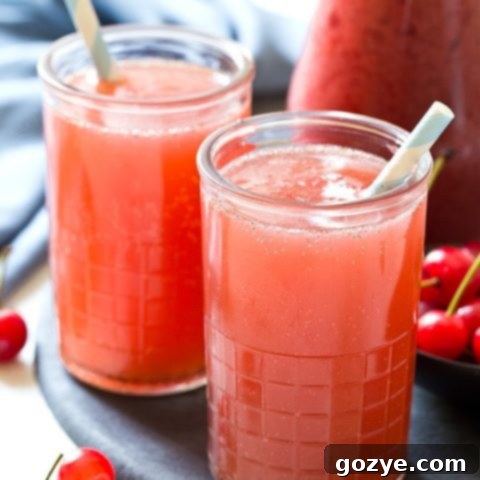 Homemade Cherry Cream Soda in a glass with a straw, garnished with fresh cherries and mint.
