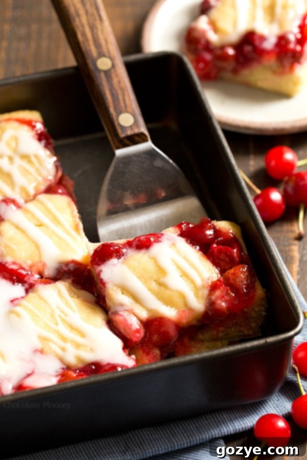 Close-up of a single Cherry Cobbler Bar revealing layers of golden-brown dough and juicy, red cherry filling.