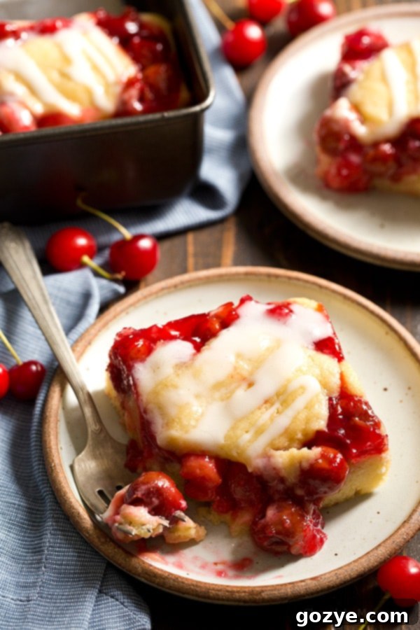 Cherry Cobbler Bars with glaze and a bite taken out, perfect for social sharing.