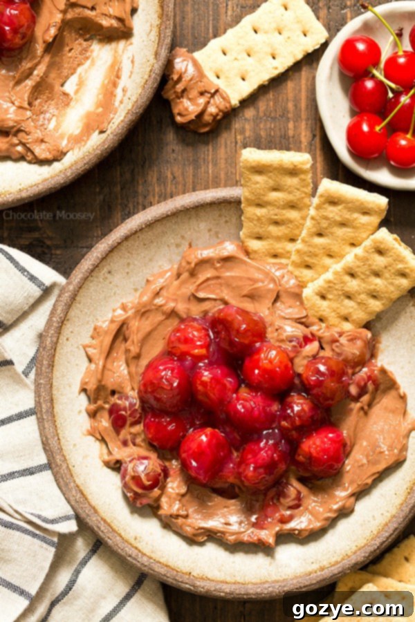 Decadent Chocolate Cherry Cheesecake Dip 5 Overhead view of Chocolate Cherry Cheesecake Dip ready to be served, with a spoon in one bowl and a dipper in another