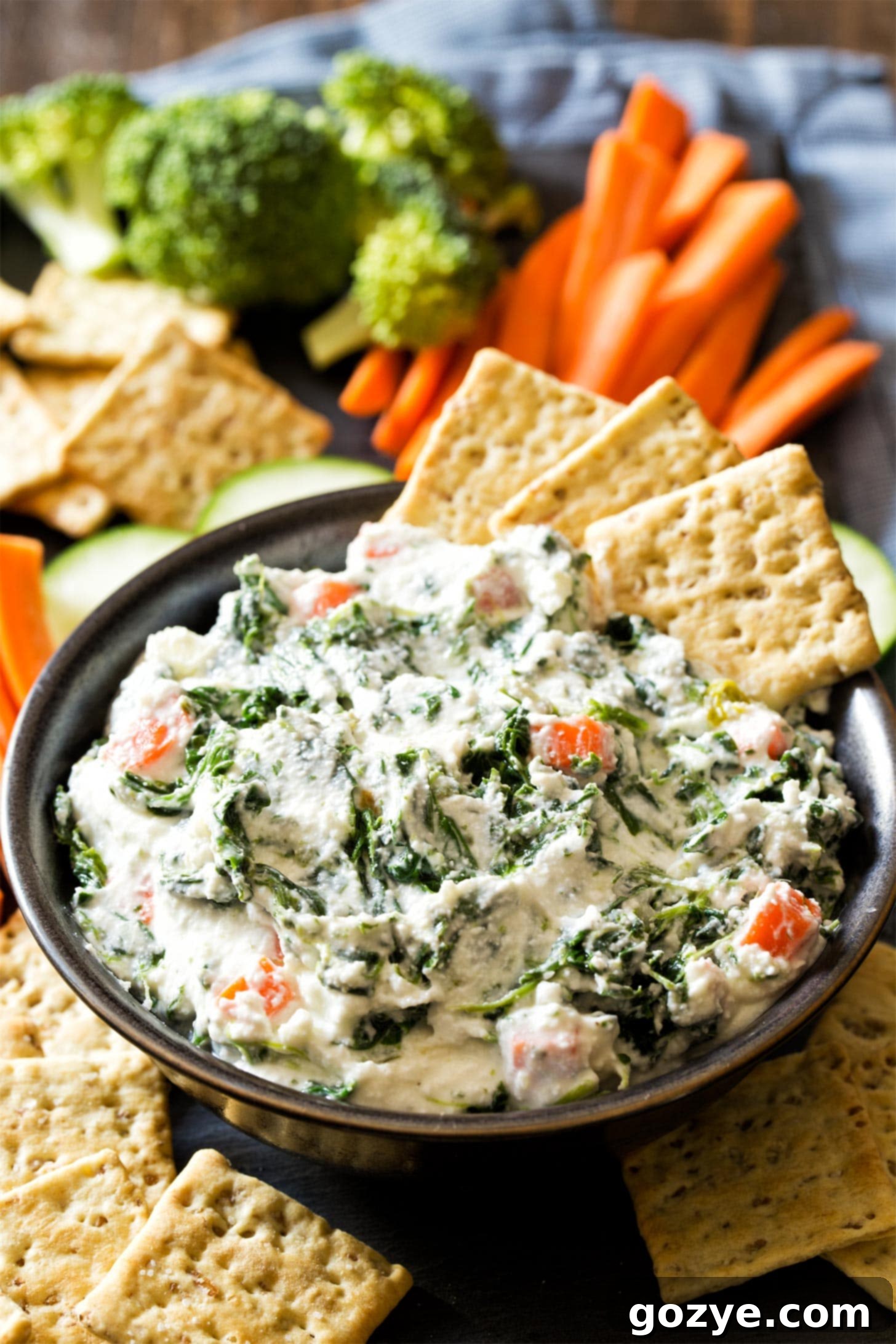 Ranch Spinach Dip in a black bowl with crackers and fresh vegetables
