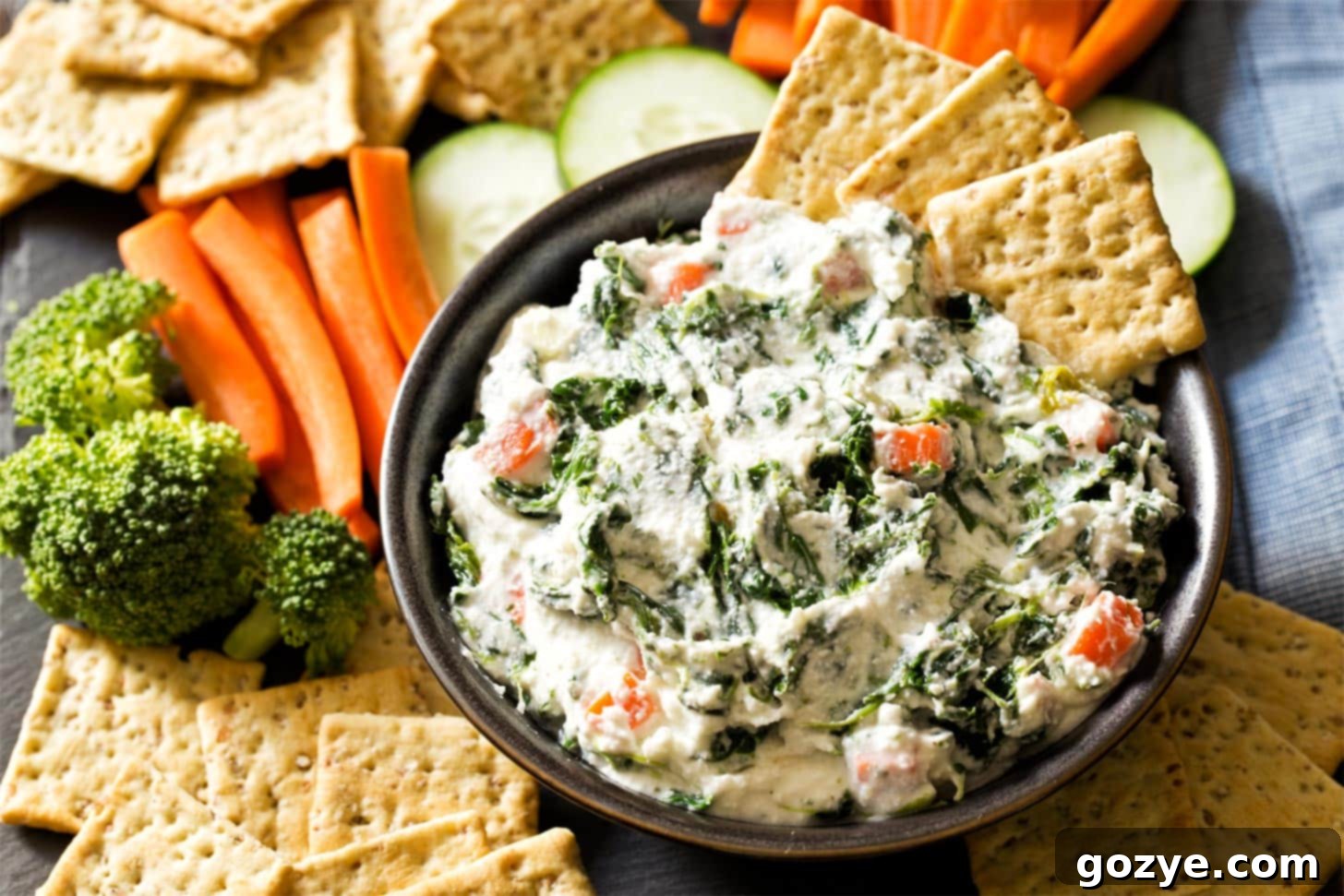 Spinach Dip with ranch in a black bowl, garnished with fresh dill and served with crackers