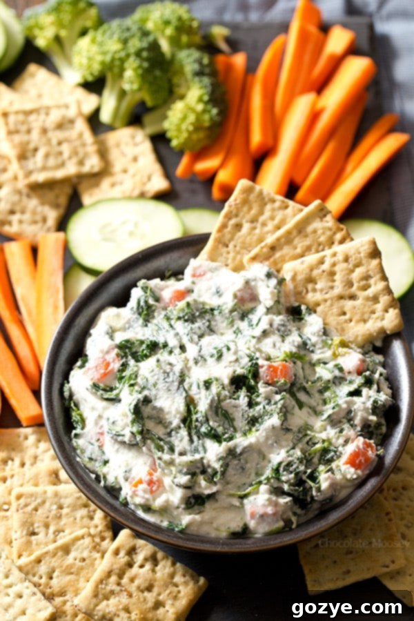 Cottage cheese spinach dip in a serving bowl with an assortment of crackers around it