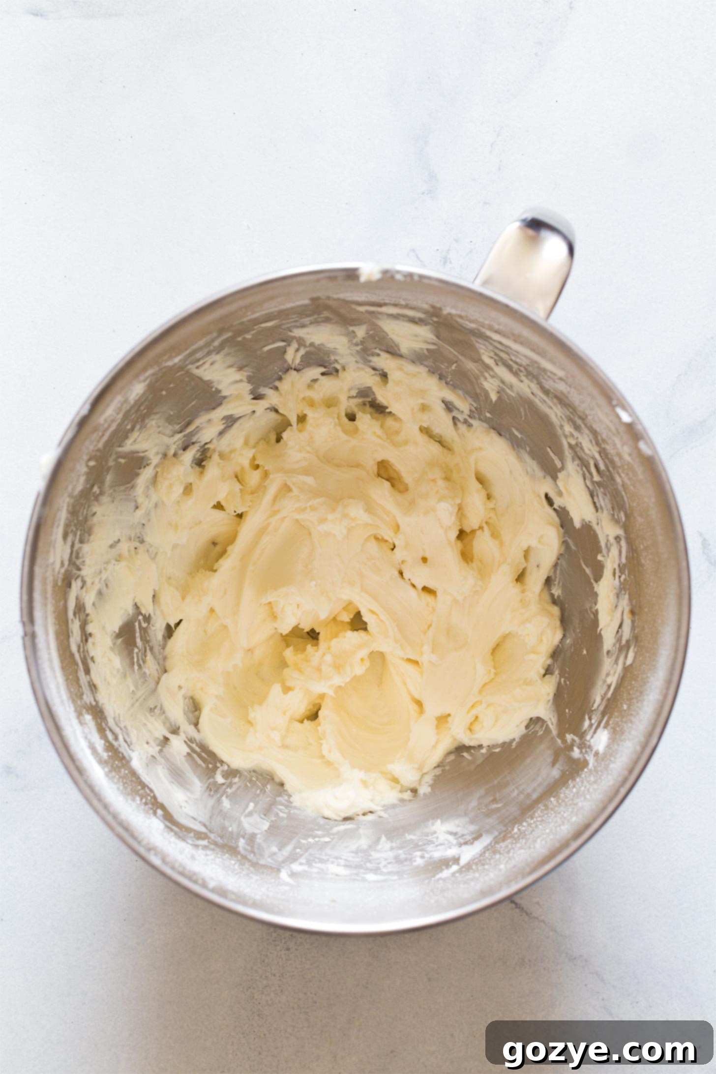 Beating together cream cheese and sugar to create the smooth cheesecake filling.