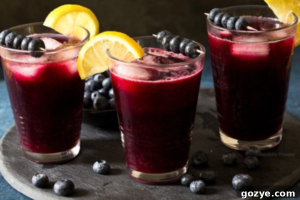 Full pitcher of homemade Sparkling Blueberry Lemonade on a table outdoors