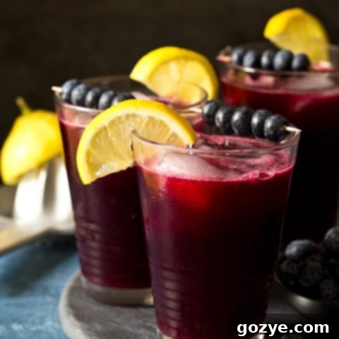 Sparkling Blueberry Lemonade in a glass with a pitcher in the background