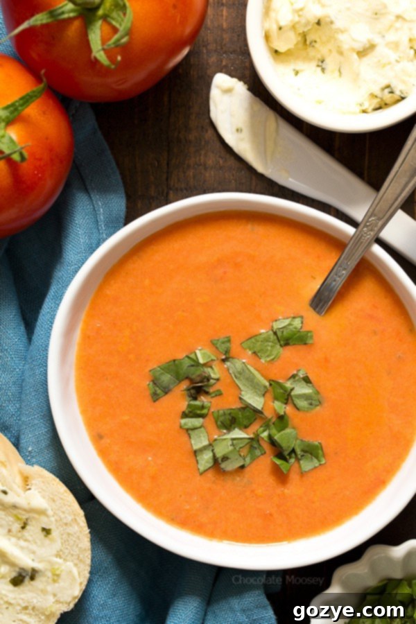 Homemade tomato soup with a side of bread and basil herb butter.