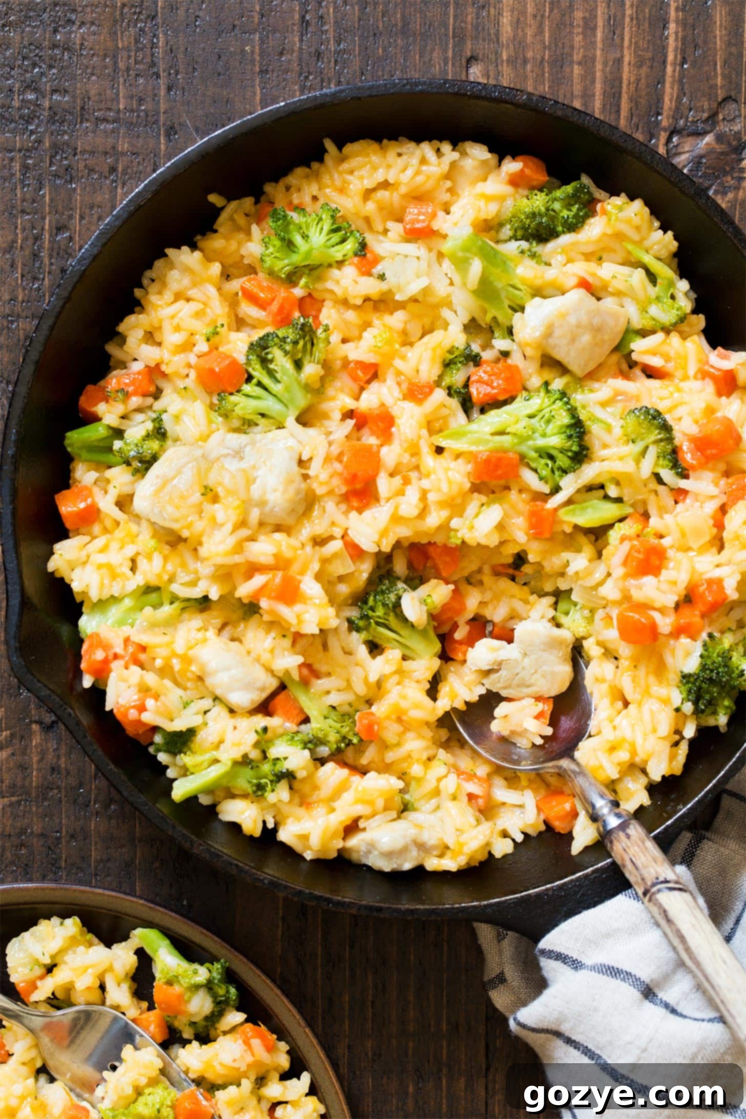 Spoon serving cheesy chicken broccoli rice from skillet