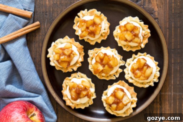 Close-up of phyllo cups filled with creamy cheesecake and apple pie topping.