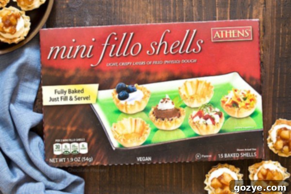 Three no-bake apple pie cheesecake phyllo cups on a white plate, showcasing the layers.