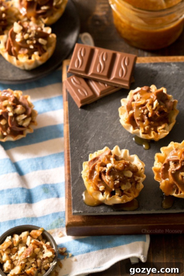 Mini No Bake Turtle Cheesecake Phyllo Cups 2 A festive platter of No-Bake Turtle Cheesecake Phyllo Cups with chocolate, caramel, and pecans, perfect for sharing.