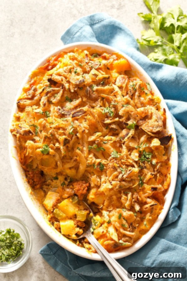 Cheesy Chorizo Potatoes baking in a white casserole dish, topped with golden French fried onions
