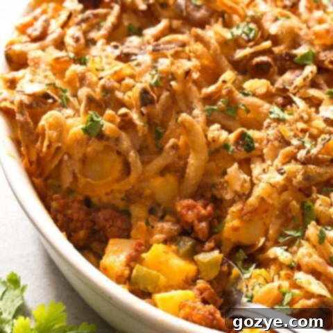 Cheesy Chorizo Potatoes in a white casserole dish with a serving spoon