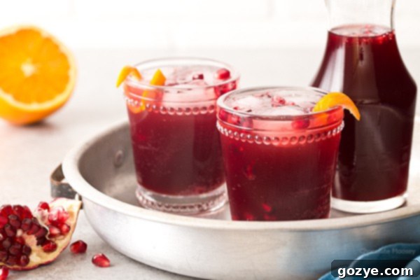 A top-down view of Pomegranate Prosecco Punch in glasses, garnished with a vibrant orange twist
