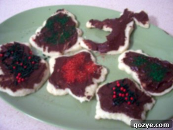 A close-up of several decorated sugar cookies with sprinkles and simple icing, showcasing holiday shapes.
