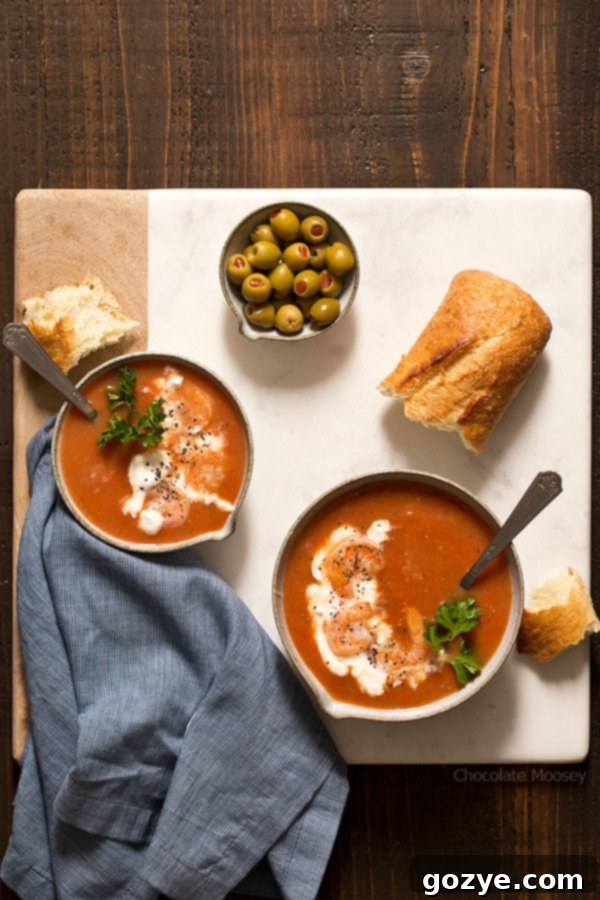 A bowl of One-Pot Bloody Mary Tomato Soup with Shrimp, garnished with sour cream and parsley.