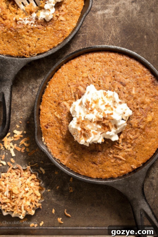 Three beautifully baked Toasted Coconut Skillet Cakes, each in its own cast iron skillet, showcasing the golden-brown exterior and rustic charm of skillet baking. The cakes are artfully arranged, highlighting their simple elegance.