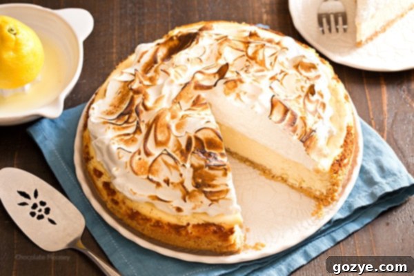 A side view of the Lemon Meringue Cheesecake, showcasing the distinct layers of crust, lemon filling, and meringue.