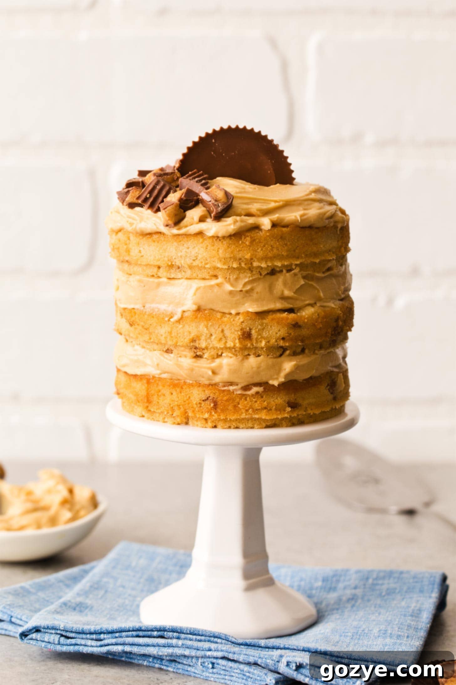 Peanut Butter Birthday Cake on a mini white cake stand, garnished with a peanut butter cup