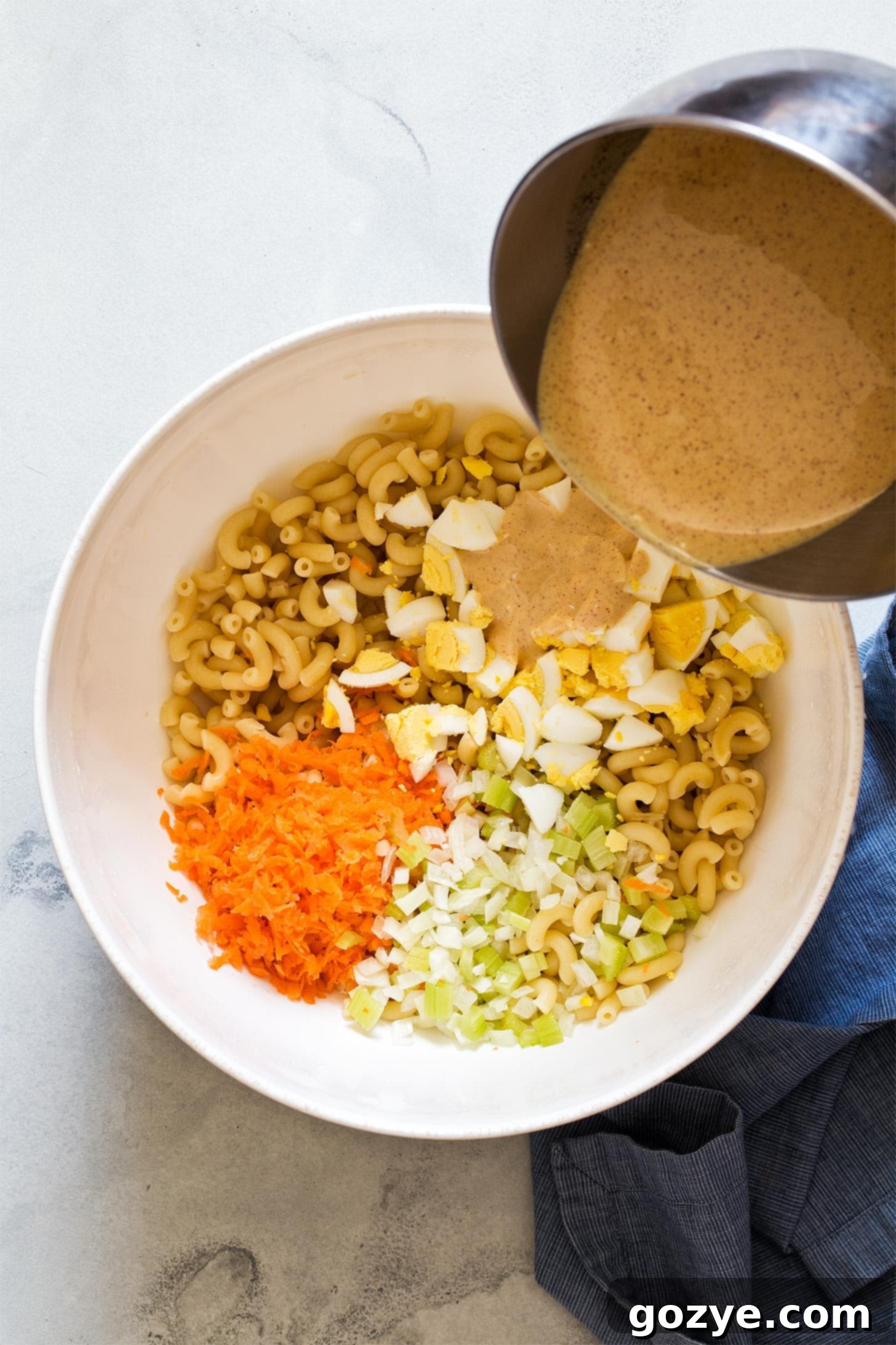 Pouring dressing over Amish macaroni salad