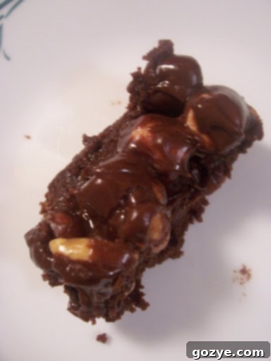 Close-up of a perfectly cut square of Rocky Road Brownie, showing layers of chocolate, marshmallow, and peanuts.