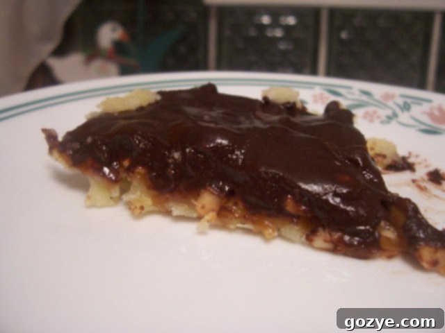 A close-up view of a Chocolate-Crunched Caramel Tart, showing the delicate layers of crust, caramel, and chocolate ganache.