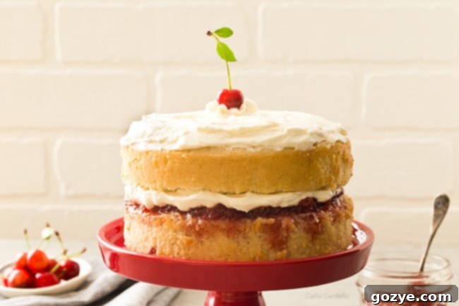 A beautifully decorated whole 6-inch cherry vanilla cake, topped with fluffy whipped cream and a few fresh cherries as garnish.