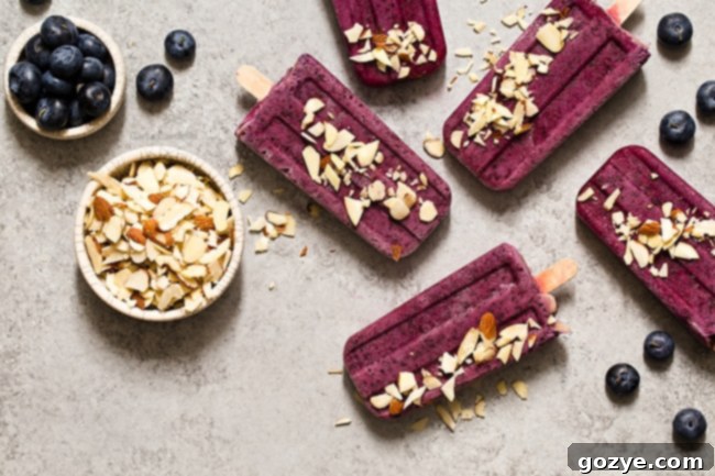 Partially frozen blueberry yogurt popsicles with sticks inserted.