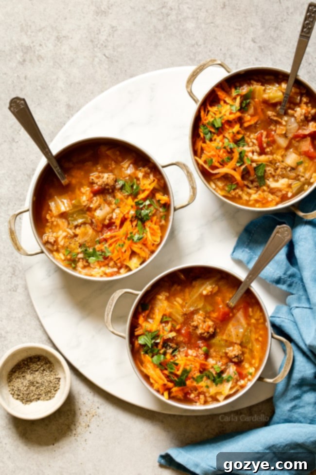 Hearty Stuffed Cabbage Soup in a bowl, with a spoon ready to serve. The soup features ground beef, rice, tomatoes, and visible pieces of tender cabbage, offering the comfort of traditional cabbage rolls without the effort.