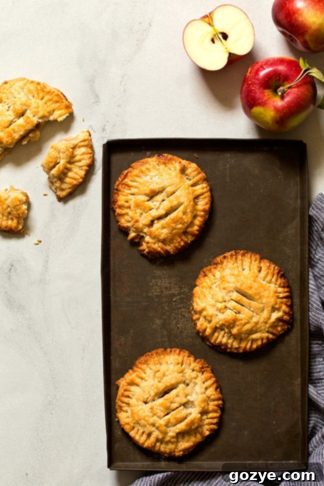 Golden brown small batch apple hand pies cooling on a wire rack, with steam rising, made with flaky pie crust and homemade apple filling.