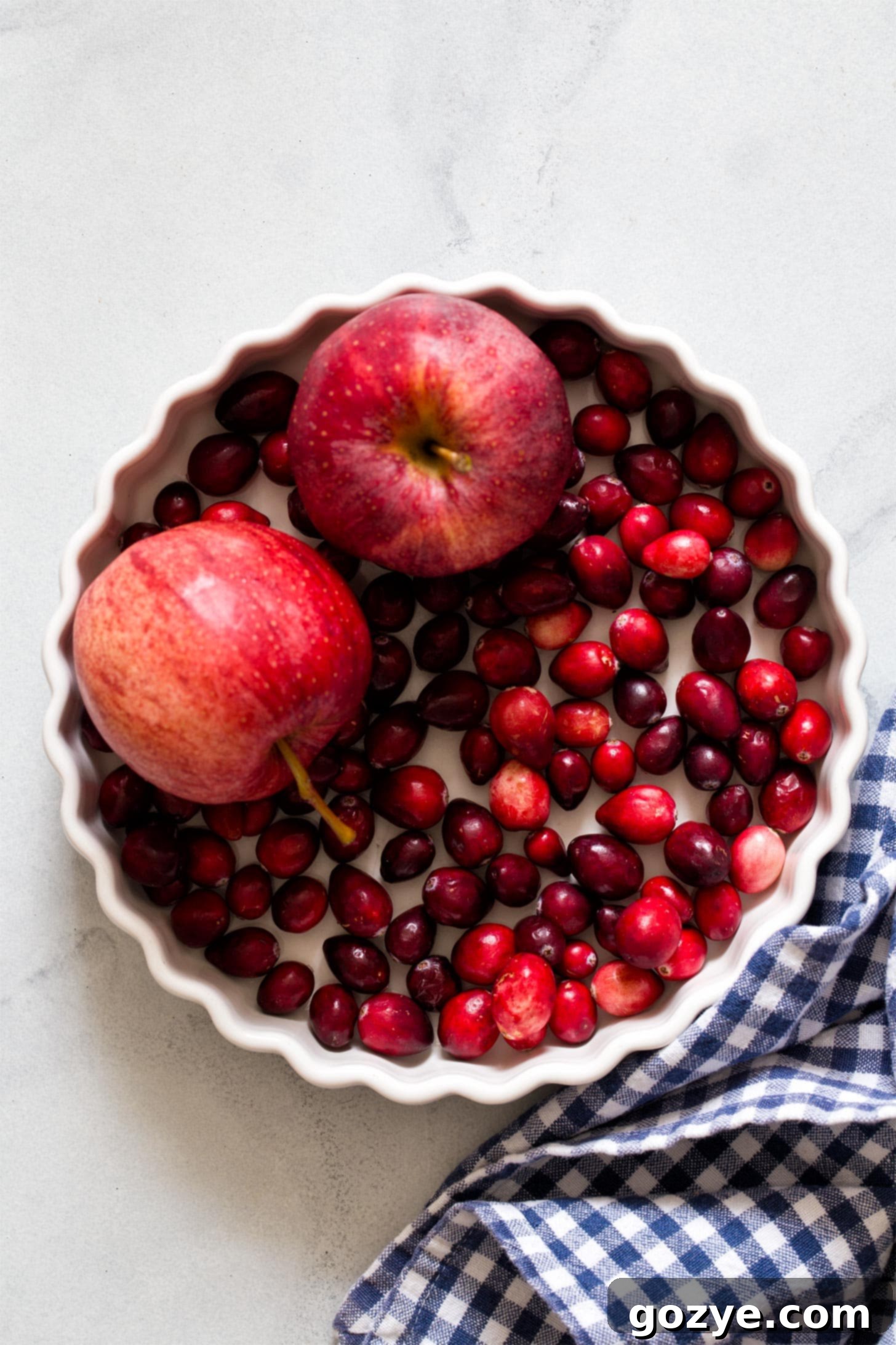 Apples and cranberries in white pan ready for crisp