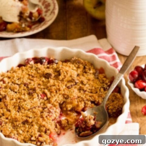 Cranberry apple crisp in white pan with a serving scooped out