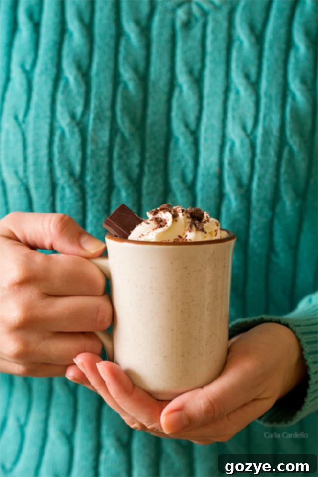Woman in turquoise sweater holding mug of thick hot chocolate